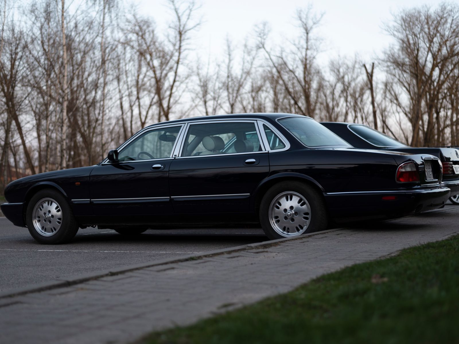 A black sedan waits on a tree-lined London street